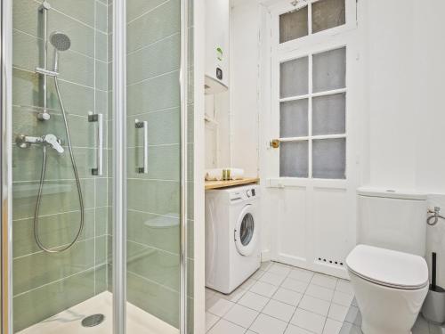 une salle de bain blanche avec douche et toilettes dans l'établissement Élégant Appartement à Paris 16e, à Paris
