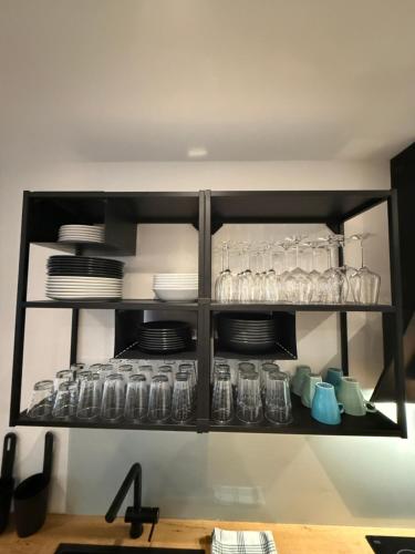 a black shelf with dishes and glasses on it at Schönes City Design Apartment I Boxspring I P I Smart I Wasch I 200m Bahnhof in Ibbenbüren