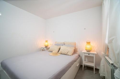 a white bedroom with a bed with a hat on it at One bedroom apartment next to the port in Fuengirola