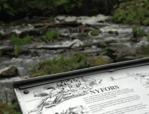 a sign in front of a river with rocks at Lilla Sjölyckan in Tyresö