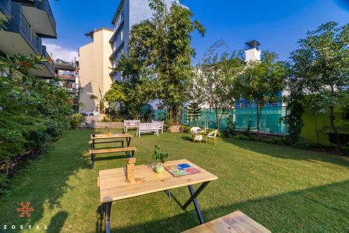 a yard with benches and tables in the grass at Zostel Rishikesh, Tapovan in Rishīkesh