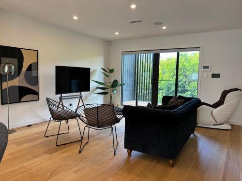 a living room with a couch and chairs and a tv at Epsom Tidy House Unit 6 in Auckland