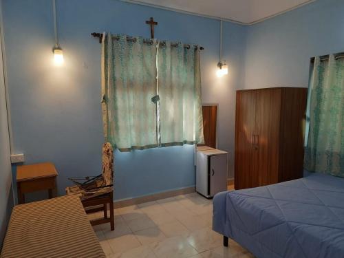 a bedroom with a bed and a cross on the wall at Casa Amarela in Cuncolim