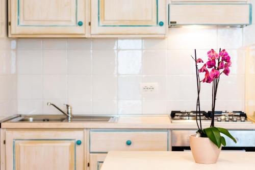 a kitchen with a vase with pink flowers in it at Le Residenze del Baia Marina in Orosei