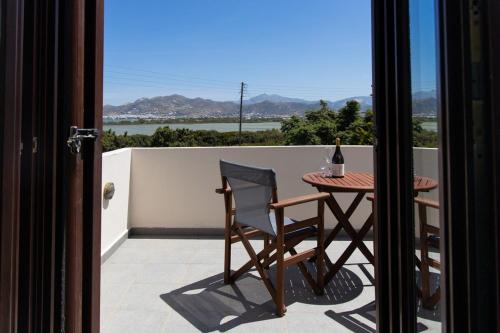 a table and chair on a balcony with a bottle of wine at Fabulous Holiday Villa in Naxos Island in Agios Prokopios