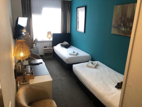 a hotel room with two beds and a chair at Hotel de Keizerskroon Hoorn in Hoorn