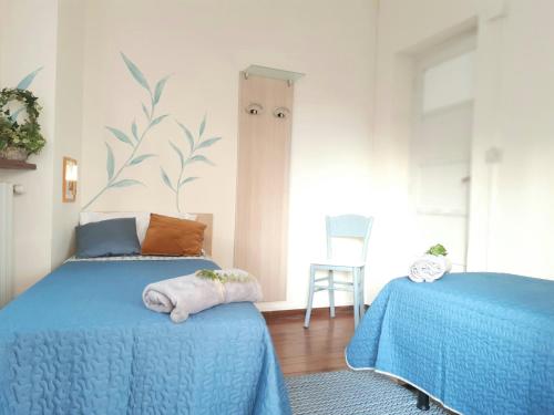 a bedroom with two beds with blue sheets and a chair at La casetta in Candelo