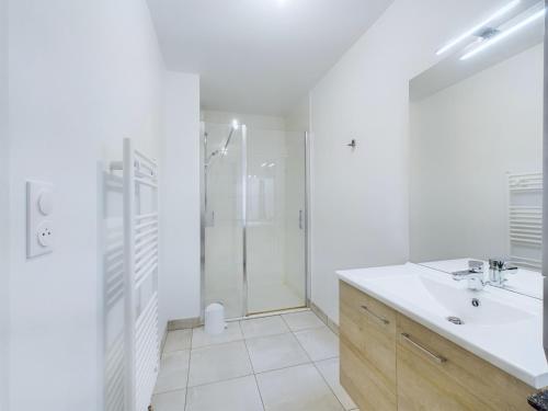 une salle de bain blanche avec une douche et un lavabo dans l'établissement Vue sur mer et plage, appartement pour 4, à Pléneuf-Val-André