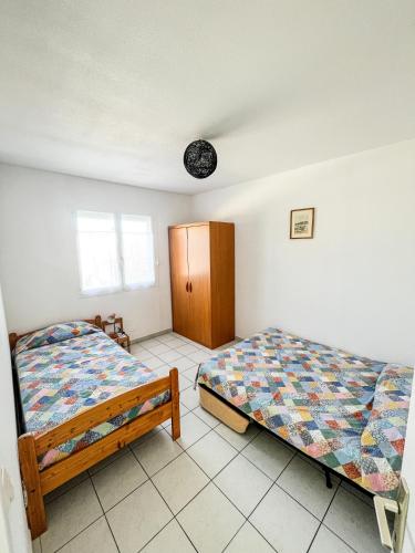 - une chambre avec deux lits et une armoire dans l'établissement Villa Marguerite, à Mèze