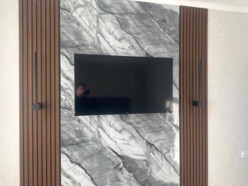 a flat screen tv on a marble wall at 1 комнатная квартира Lux класса в центре Шымкента in Shymkent