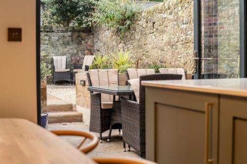 a patio with chairs and tables and a stone wall at Logies Cottage in St. Andrews