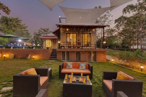 a house with two couches and a table in the yard at SaffronStays Dew Drops in Dhamni