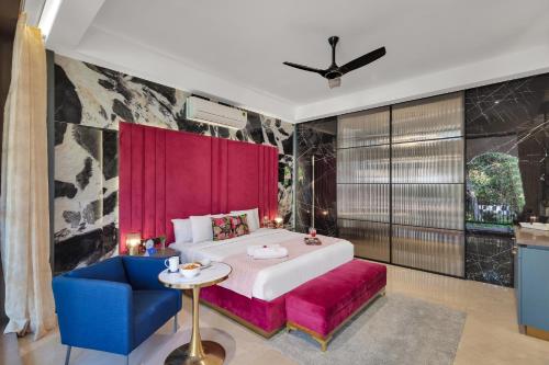 a bedroom with a large bed and a blue chair at SaffronStays Dew Drops in Dhamni