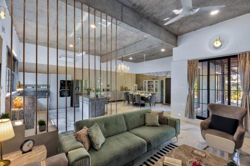 a living room with a green couch and a dining room at SaffronStays Dew Drops in Dhamni