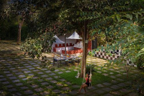 a woman sitting on a swing under a tree at SaffronStays Dew Drops in Dhamni