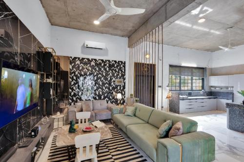 a living room with a couch and a tv at SaffronStays Dew Drops in Dhamni