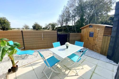 un patio avec une table et des chaises et une clôture dans l'établissement Maisonnette Ultra cosy Bord de mer Terrasse, à Guidel