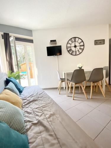 - un salon avec un lit, une table et une horloge dans l'établissement Maisonnette Ultra cosy Bord de mer Terrasse, à Guidel