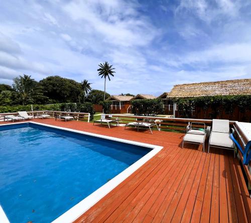 una piscina en una terraza de madera con sillas y una casa en Red Hibiscus Villas, en Rarotonga