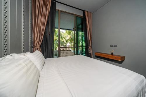 un lit blanc dans une chambre avec une fenêtre dans l'établissement Saturdays by Lotus Heart, à Ban Saiyuan (1)