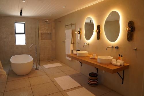 a bathroom with two sinks and a tub and two mirrors at Ochre and Ash in Clanwilliam