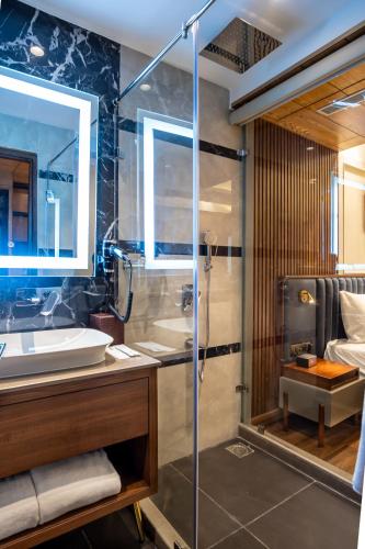 a bathroom with a glass shower and a sink at The Kleo Hotel in Zirakpur