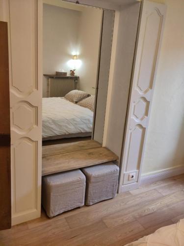a mirror in a bedroom with two stools and a bed at L'ENVOLEE in Champdeniers-Saint-Denis