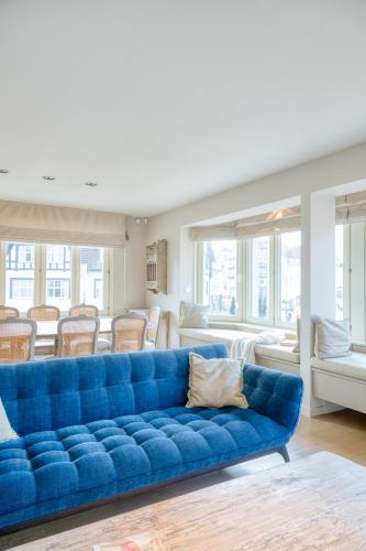a blue couch in a living room with chairs at Stunning 3-Bedroom apartment with panoramic view in De Haan