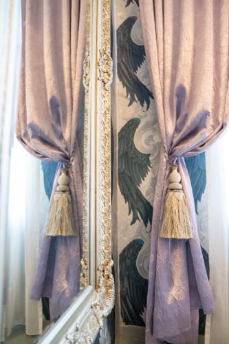 a mirror with a reflection of a window with curtains at Hotel Urania in Vienna