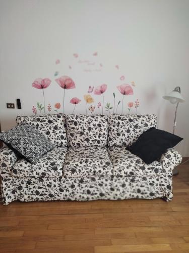 a couch in a room with a wall with flowers at B&B DUE ABETI in Florence