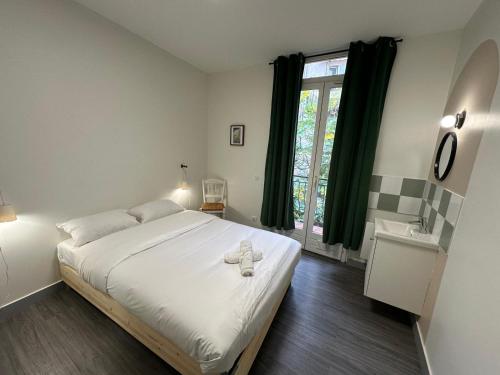 une chambre avec un grand lit blanc et une fenêtre dans l'établissement Maison spacieuse et lumineuse, à Saint-Étienne