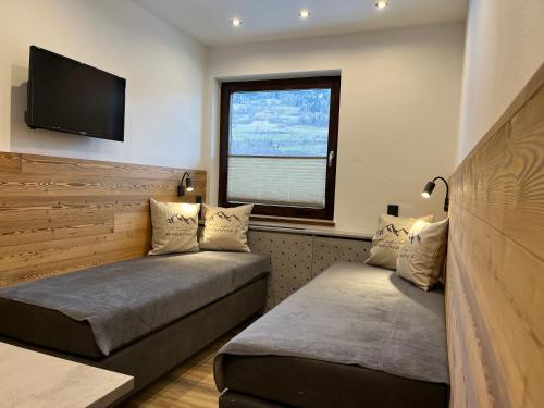 a bedroom with two beds and a flat screen tv at Pension Kreischberg Mayer in Sankt Lorenzen ob Murau