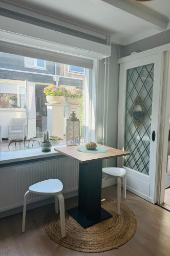 a table and two stools in a room with a window at Hello Katwijk - Zomerhuis Paul Krügerstraat 3 in Katwijk aan Zee
