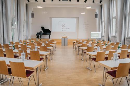ein Zimmer mit Tischen, Stühlen und einem Klavier in der Unterkunft Gästehaus Auf dem Heiligen Berg B&B in Wuppertal