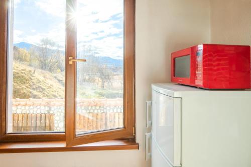 a red microwave sitting on a counter next to a window at Cozy Luxurious Apartment Next to Borovets and Rila mountain in Govedartsi