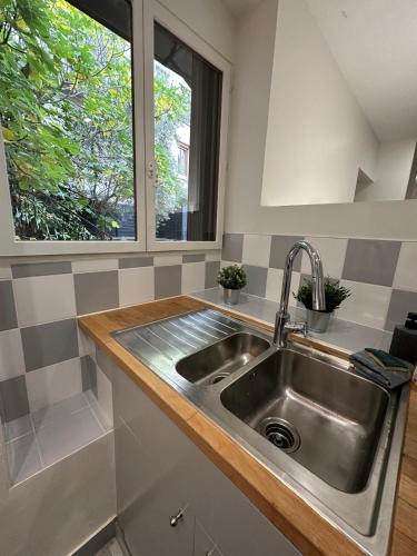 une cuisine avec un évier en acier inoxydable et une fenêtre dans l'établissement Maison spacieuse et lumineuse, à Saint-Étienne