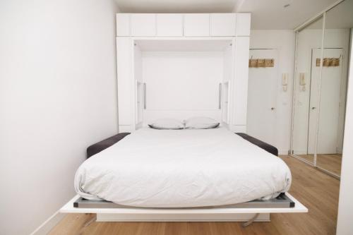 - un lit blanc dans une chambre avec un miroir dans l'établissement Charmant studio près de Montmartre, à Paris