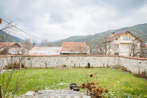 a yard with a stone wall and a house at Cozy Luxurious Apartment Next to Borovets and Rila mountain in Govedartsi