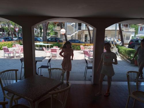 two girls are standing in a porch with a table and chairs at Hotel Toschi in Lido di Classe