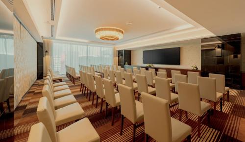 a conference room with white chairs and a flat screen tv at Millennium Al Masar in Jeddah