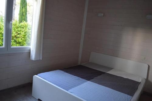 un lit blanc dans une chambre avec une fenêtre dans l'établissement Gasmim79 - Maison pour 6 personnes située dans un parc arboré à Gassin, à Gassin