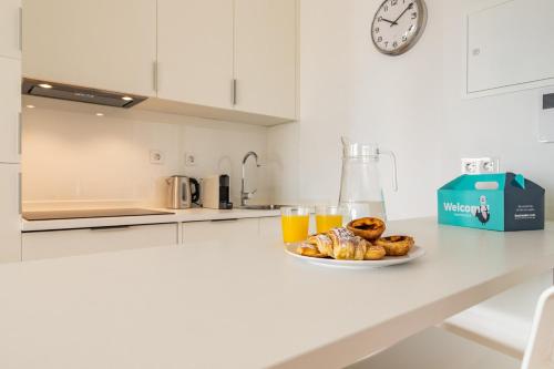 a plate of pastries and orange juice on a kitchen counter at Belem Design Apartments by Homing in Lisbon