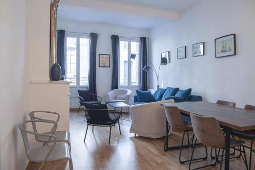 un salon avec une table et un canapé bleu dans l'établissement La Comédie, appart de Charme, à Montpellier