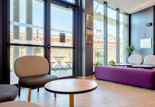 a waiting room with a purple couch and tables at B&B HOTEL Toulon Centre Gare in Toulon