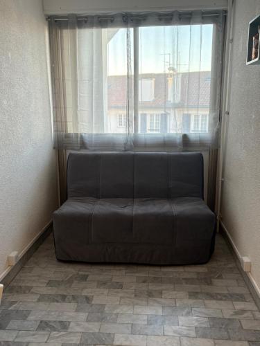 un canapé installé devant une fenêtre dans l'établissement Hendaye plage, à Hendaye