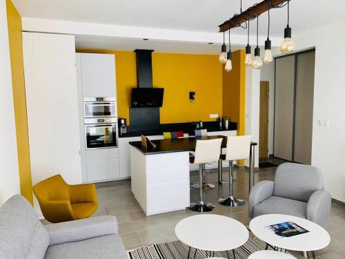 un salon avec une cuisine aux murs jaunes dans l'établissement L Olympe Terrasse Parking Wifi, à La Rochelle