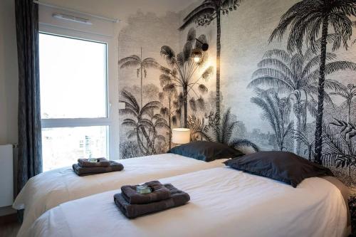- 2 lits dans une chambre ornée d'une fresque murale de palmiers dans l'établissement L Olympe Terrasse Parking Wifi, à La Rochelle