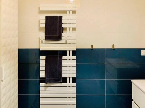 La salle de bains est pourvue de serviettes et de carrelage bleu et blanc. dans l'établissement L Olympe Terrasse Parking Wifi, à La Rochelle