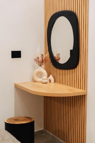 a wooden shelf with a mirror and a stool at Erthā Suites with private pools in Vóthon