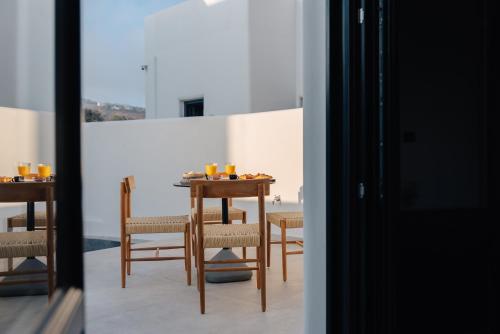 a dining room with a table and chairs and a window at Erthā Suites with private pools in Vóthon